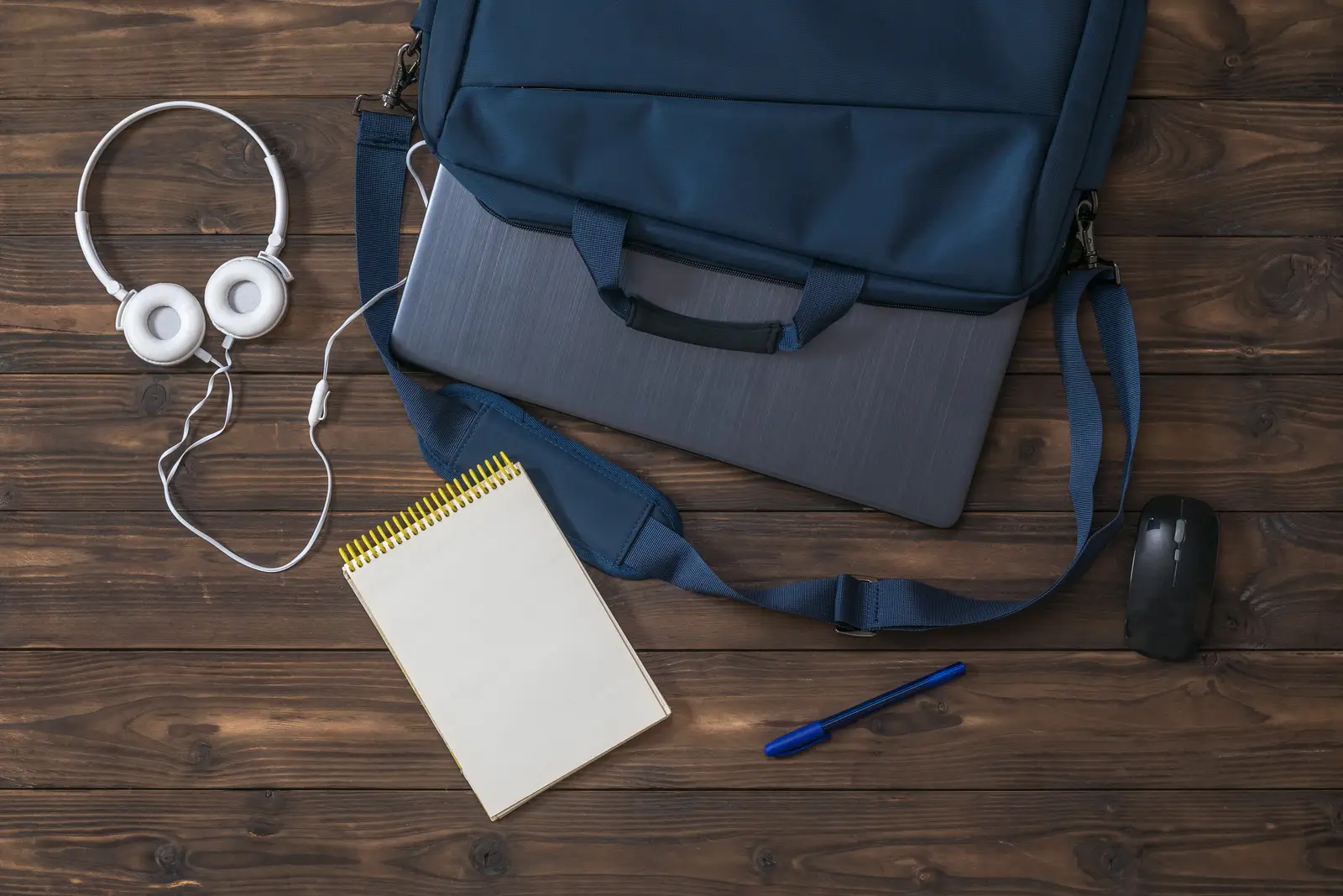 Laptop bag packed with headphones, notepad and mouse for an office day