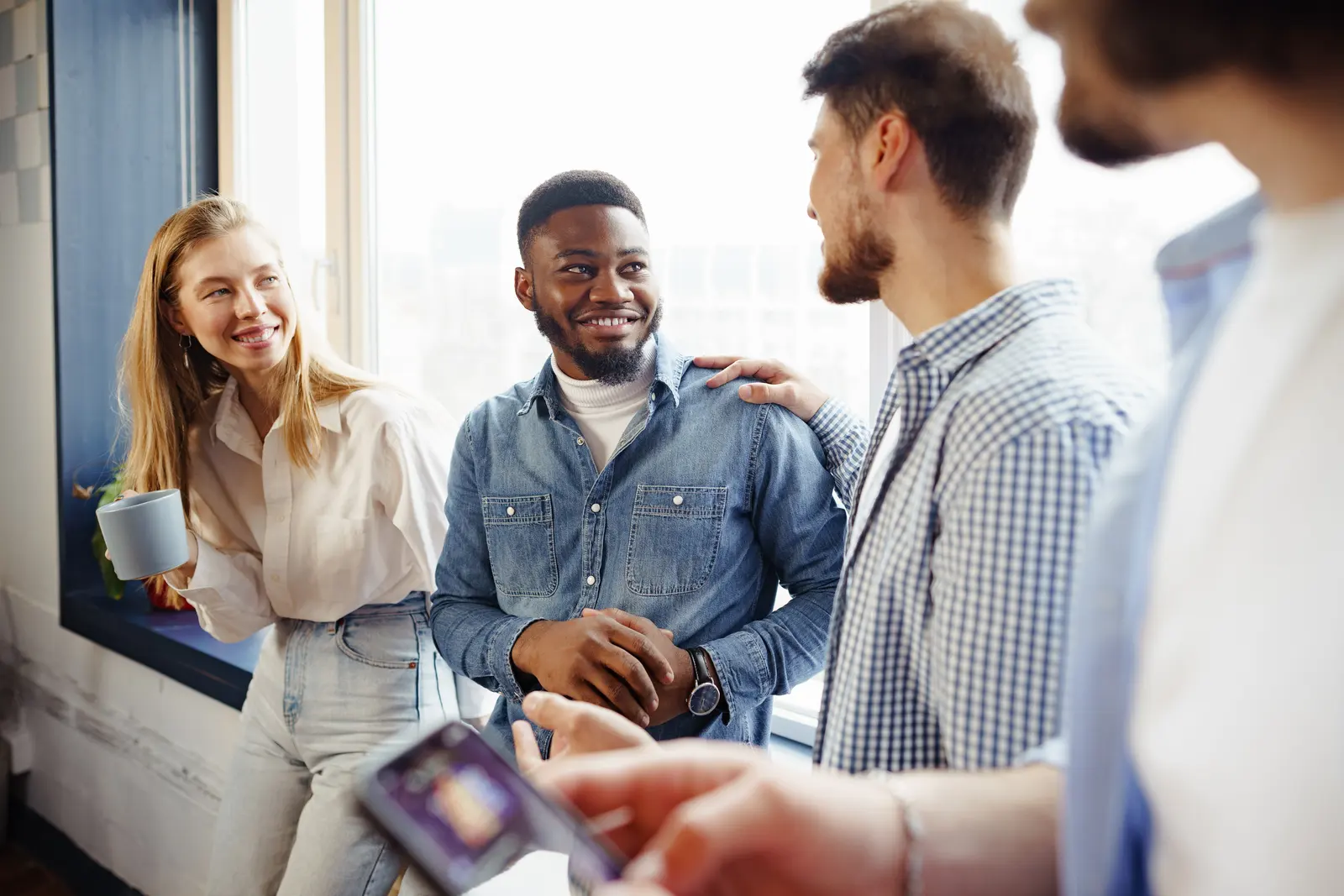 Colleagues laughing together during a coffee break in the office