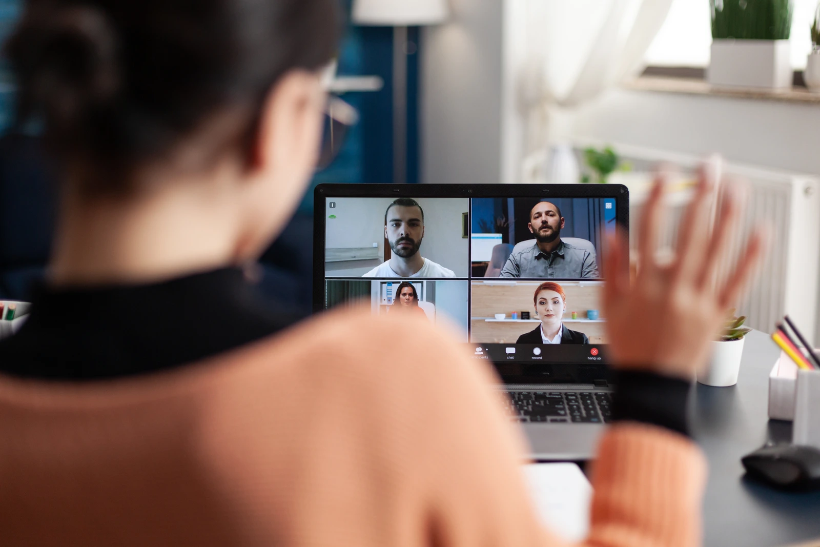 Remote worker waving to colleagues on a team video call