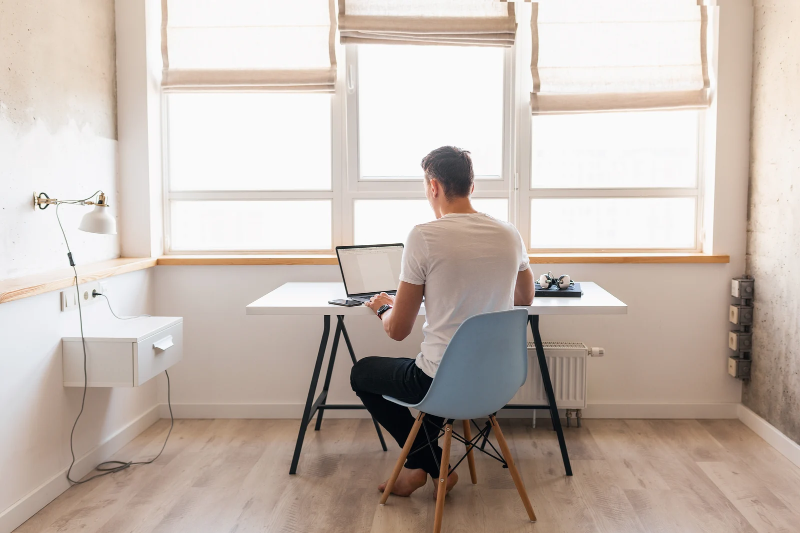 Man working on a laptop at a desk in a bright home office